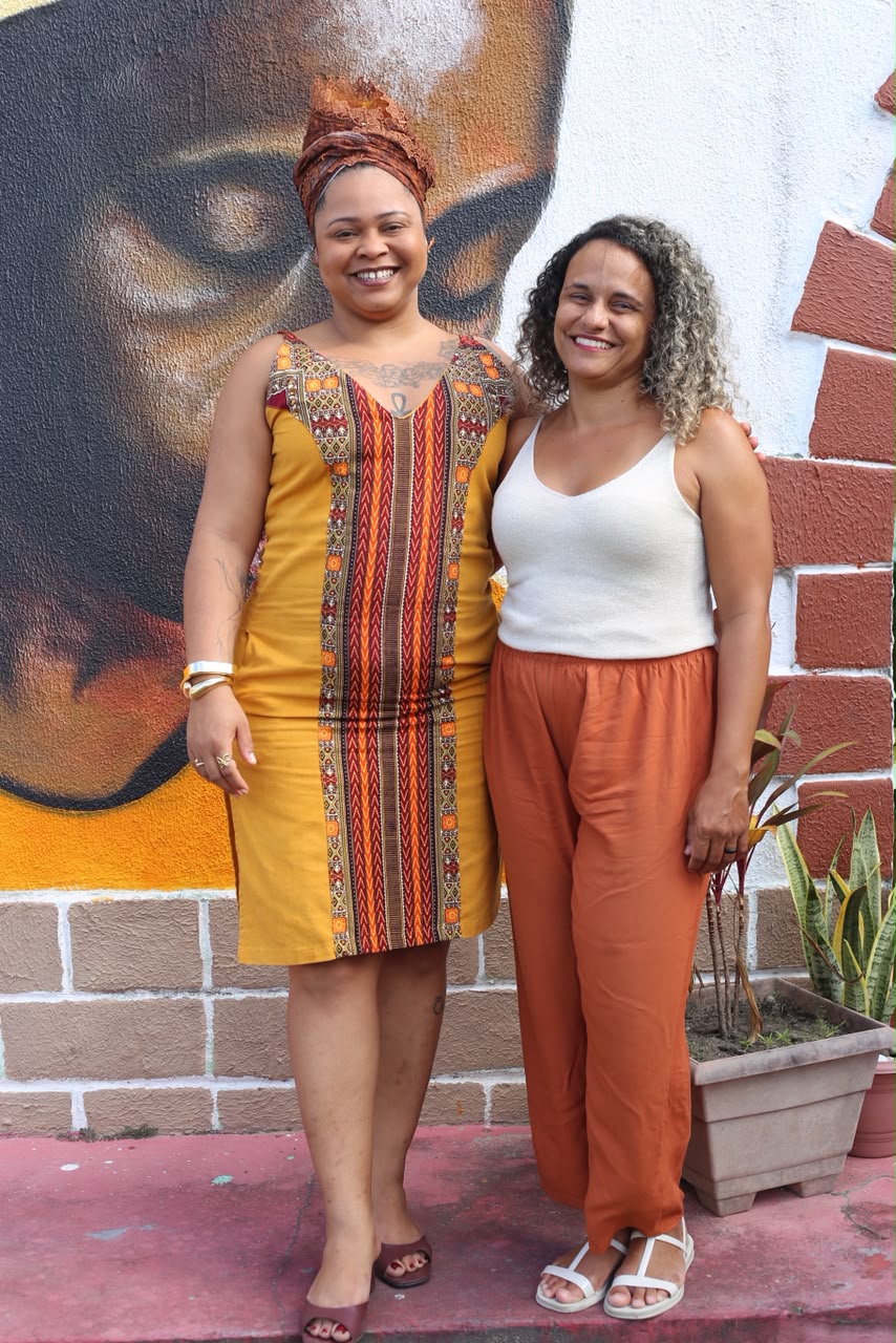 Tayná Passos e Priscila Xavier diante de mural